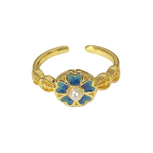 Close-up of vintage gold open ring featuring a blue enameled flower with pearl center