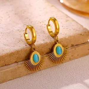 Detailed macro view of gold-plated stainless steel sunburst earrings with turquoise stone