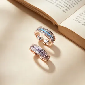 Detail view of luxury rose gold open rings with turquoise and violet stones on a book