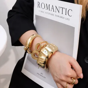 Détail rapproché de bracelets larges dorés irréguliers sur le bras d'un mannequin