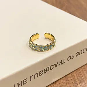 Close-up of retro gradient blue floral pattern on golden open ring band.