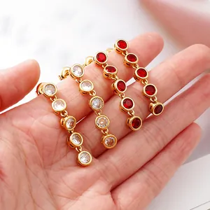 Close-up of gold stainless steel long drop earrings with clear and red round stones