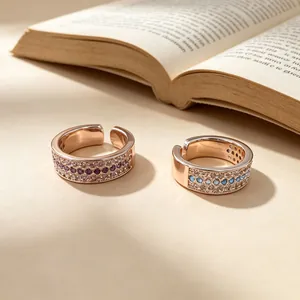 Close-up detail of two elegant rose gold rings with three rows of purple and blue crystals