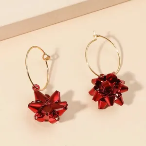 Dettaglio ravvicinato di orecchini a cerchio con fiocco rosso metallizzato per Natale