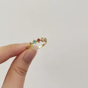 Dettaglio di un anello d'oro con vivaci zirconi quadrati multicolore incastonati.