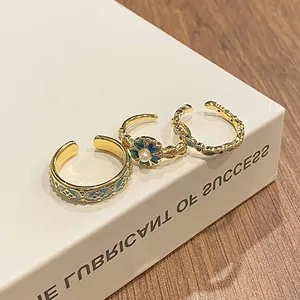 Close-up of vintage gold-plated rings with blue enamel floral and quatrefoil patterns