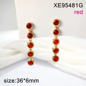 Close-up detail of elegant gold-toned long drop earrings with five round red faceted stones