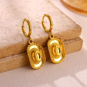 High-quality close-up detail of gold cowboy hat charm hoop earrings on a stone base