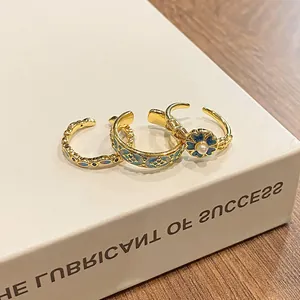 Detailed view of vintage gold rings with blue enamel patterns and a pearl accent