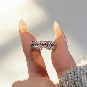 Close-up of a vintage-style ruby and diamond row ring being held in elegant sunlight