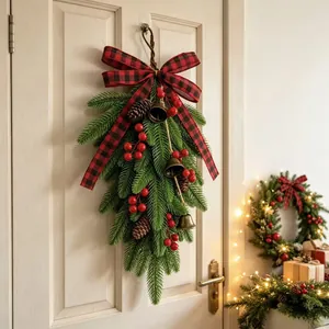Close-up of a Christmas teardrop swag with bells and red plaid bow on white door