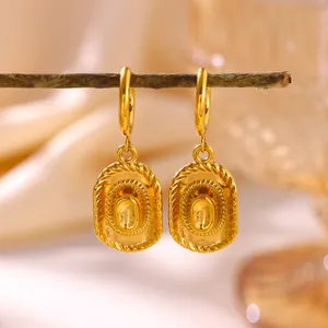 Detailed view of gold cowboy hat dangling earrings on a rustic branch