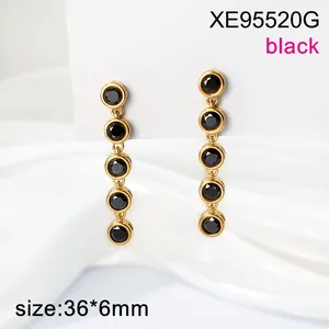 Detail of gold stainless steel long drop earrings with five black stone charms.