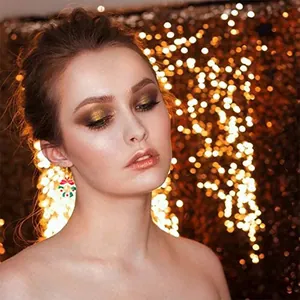 Bella modella che indossa un orecchino ghirlanda di Natale con sfondo bokeh dorato caldo