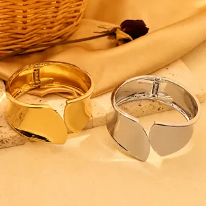Vue détaillée de bracelets ouverts à ressort en alliage or et argent sur un décor de luxe