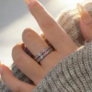 Close-up of a vintage-style silver ring with red and white stones on a finger