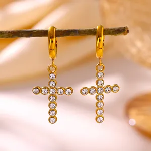 Elegant close-up of gold-plated stainless steel cross earrings with sparkling clear stones.