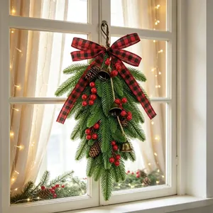 Artificial Christmas teardrop wreath with buffalo plaid bow and bells on a window