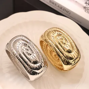 Primer plano de brazaletes de aleación dorados y plateados con diseño de espiral