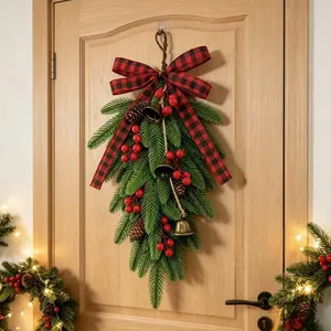 Artificial Christmas teardrop swag with red berries and buffalo plaid bow on a door.