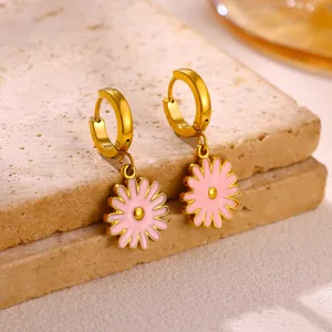 Detailed macro view of elegant pink enamel daisy earrings with gold stainless steel hoops