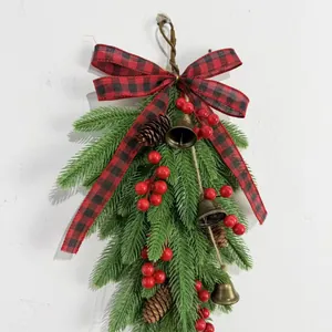 Macro detail of artificial pine branches, red berries, and vintage bells on Christmas swag