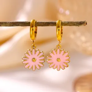 Detailed view of pink enamel daisy flower charms on golden stainless steel hoop earrings.