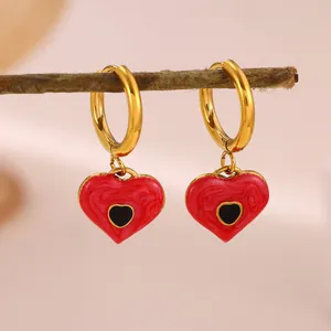 Macro view of stainless steel gold heart hoop earrings with red swirl enamel and black center