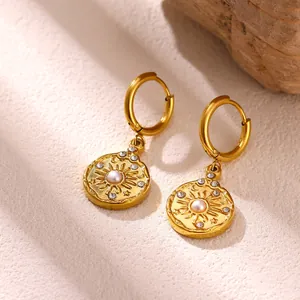 Macro detail of gold stainless steel sunburst coin drop earrings with pearl and crystal