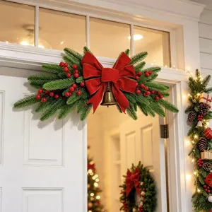 Festive Christmas lintel swag decoration with a red velvet bow and gold bell hanging on white door
