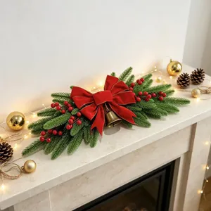 Close-up of Christmas mantel swag with pine branches, red velvet bow, and golden bell