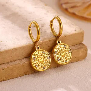 Detail view of gold stainless steel hoop earrings with heart sunburst charm and crystals