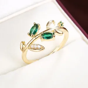 Close-up of creative gold leaf branch ring with green marquise stones
