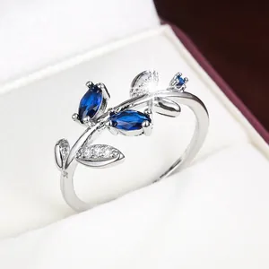 Detail view of a silver leaf-shaped ring with marquise blue stones in a gift box