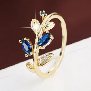Close-up macro view of a gold leaf-shaped ring featuring elegant marquise blue stones
