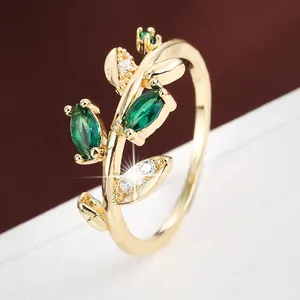 Close-up detail of leaf-shaped ring with green and white zircons in gold finish