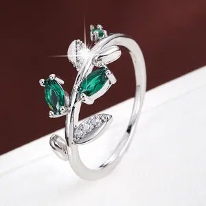 Close-up of an elegant silver branch shaped ring with sparkling green gemstones