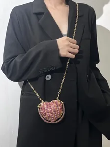 Détail d'un mini sac de soirée en forme de cœur avec strass roses et chaîne dorée.