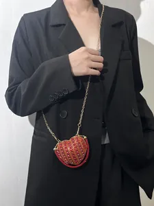 Gros plan d'un mini sac de soirée en forme de cœur en strass rouge avec chaîne