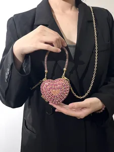 Détail d'un sac de soirée rose en forme de cœur avec strass et bandoulière chaîne