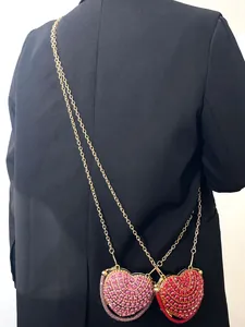 Vue de dos d'un mannequin portant deux mini sacs à bandoulière en strass en forme de cœur.