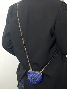 Vue détaillée d'un sac à bandoulière bleu en forme de cœur avec strass sur un blazer noir.