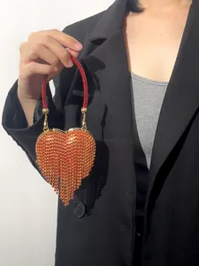 Mini sac à main de soirée élégant en strass orange en forme de cœur tenu par un modèle