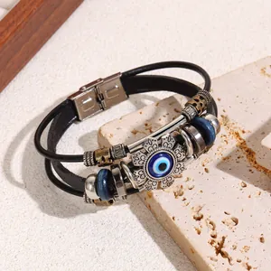 Detail view of a retro multi-layer leather bracelet with blue Evil Eye charm and wood beads.
