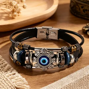 Close-up of a vintage leather bracelet featuring a detailed evil eye charm and steel clasp.