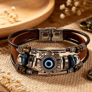 Close-up of vintage leather bracelet featuring an Evil Eye charm and stainless steel clasp.