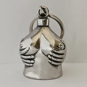 Macro view of metallic guardian bell keychain featuring an artistic hand-held breast design