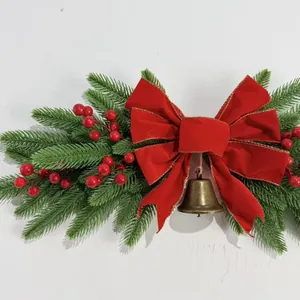 Detail of Christmas wall hanging with pine needles, red velvet bow and golden bell