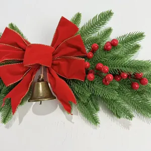 Detailed view of a Christmas wall hanging swag with red velvet bow and brass bell