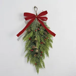 Close-up detail of a Christmas teardrop wall swag with red bow, berries and bells